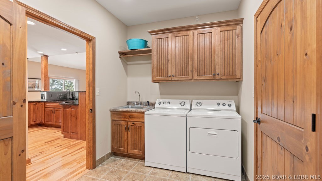 Laundry room with a washer and dryer, wood cabinets, and a utility sink.