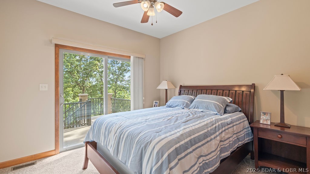 Bedroom with striped blue bedding and a sliding glass door opening onto a tree-lined balcony.