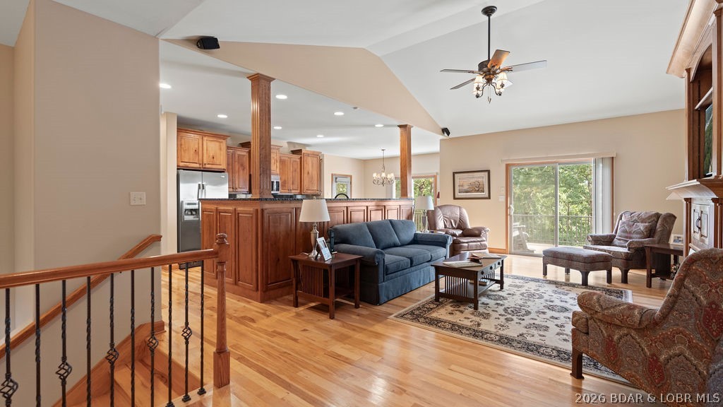 Open-plan living room and kitchen with hardwood floors, wood cabinetry, and sliding doors to a balcony.