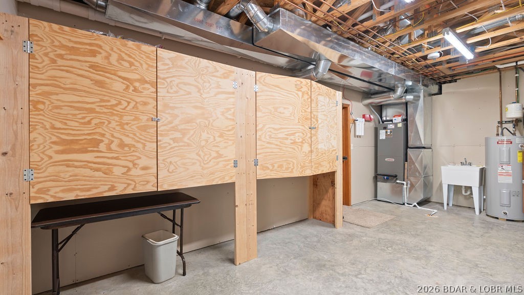 Utility room with plywood cabinets, exposed HVAC ducts, a utility sink, and a water heater.