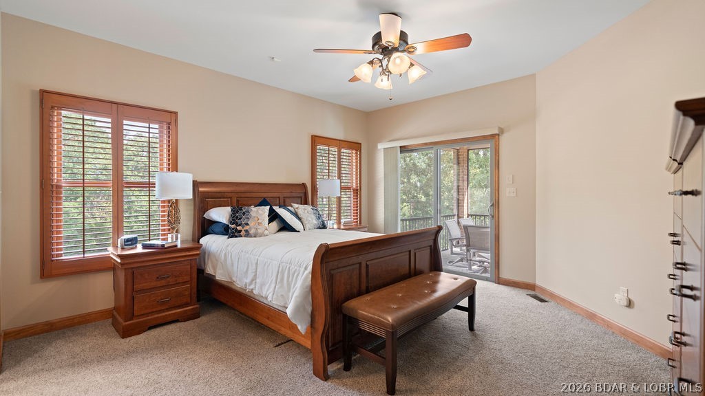 Furnished bedroom with a dark wood bed, wooden blinds, and a sliding glass door to a patio.