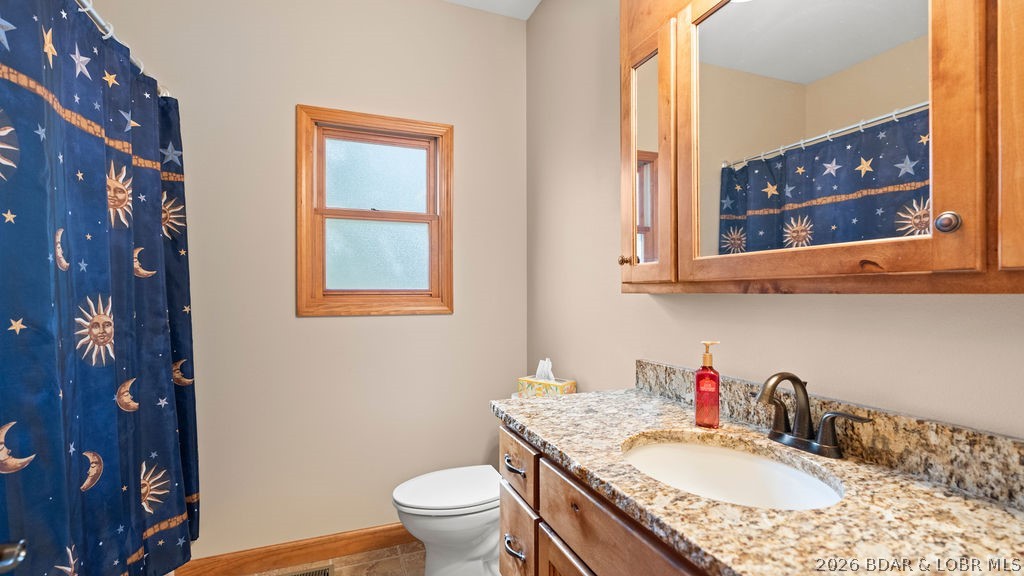 Bathroom with a granite vanity, wood cabinetry, and a celestial-patterned shower curtain.