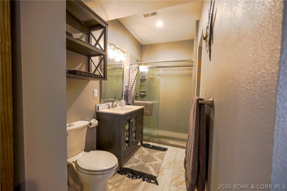 Bathroom with a dark wood vanity, toilet, and glass-enclosed shower.