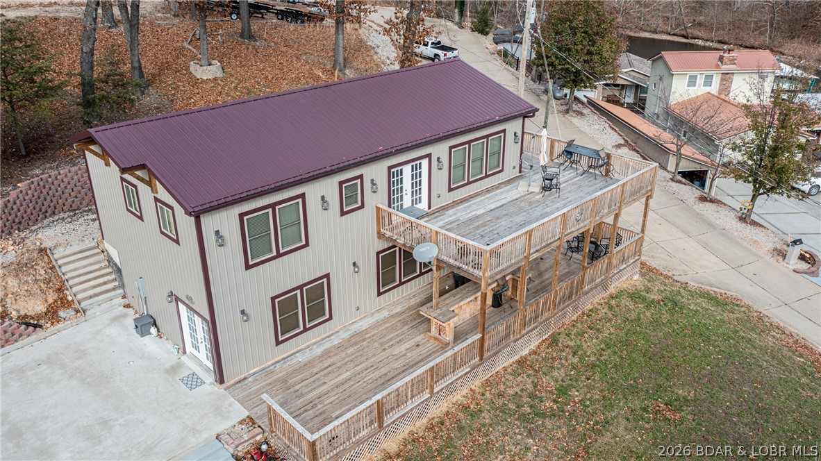 Two-story home with burgundy roof and trim, shown from above with expansive wooden decks.