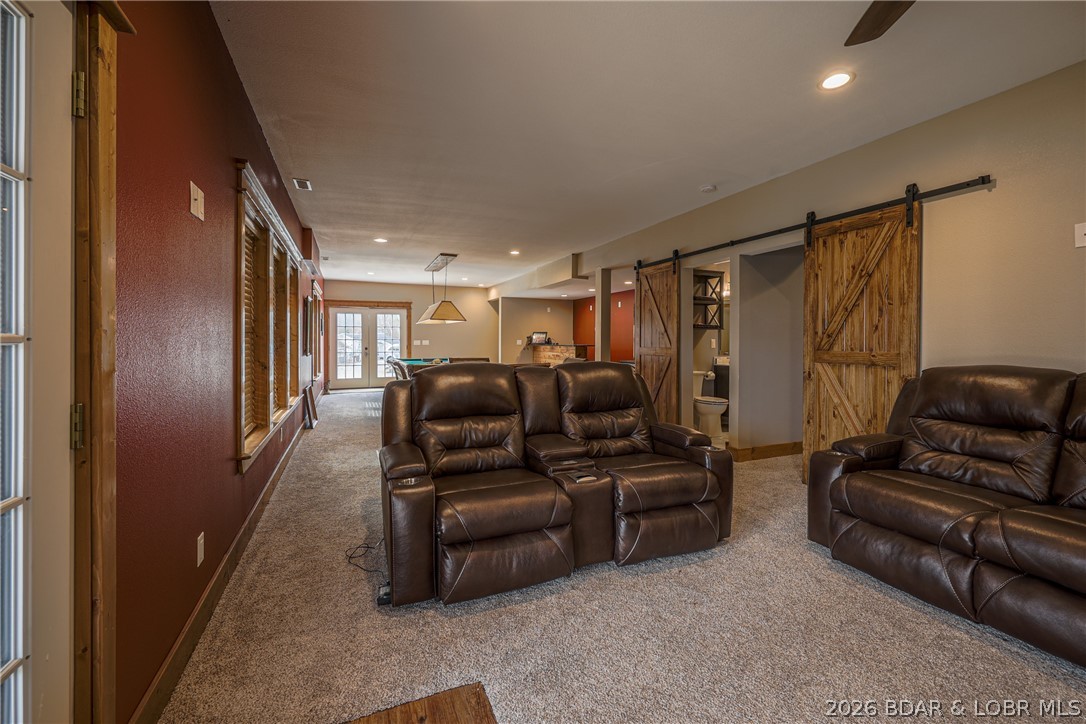 Living room with leather reclining sofas, carpet, and rustic sliding barn doors.