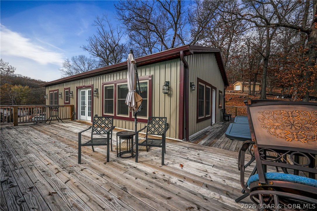 Home with burgundy trim and metal siding, viewed from a spacious furnished wood deck.