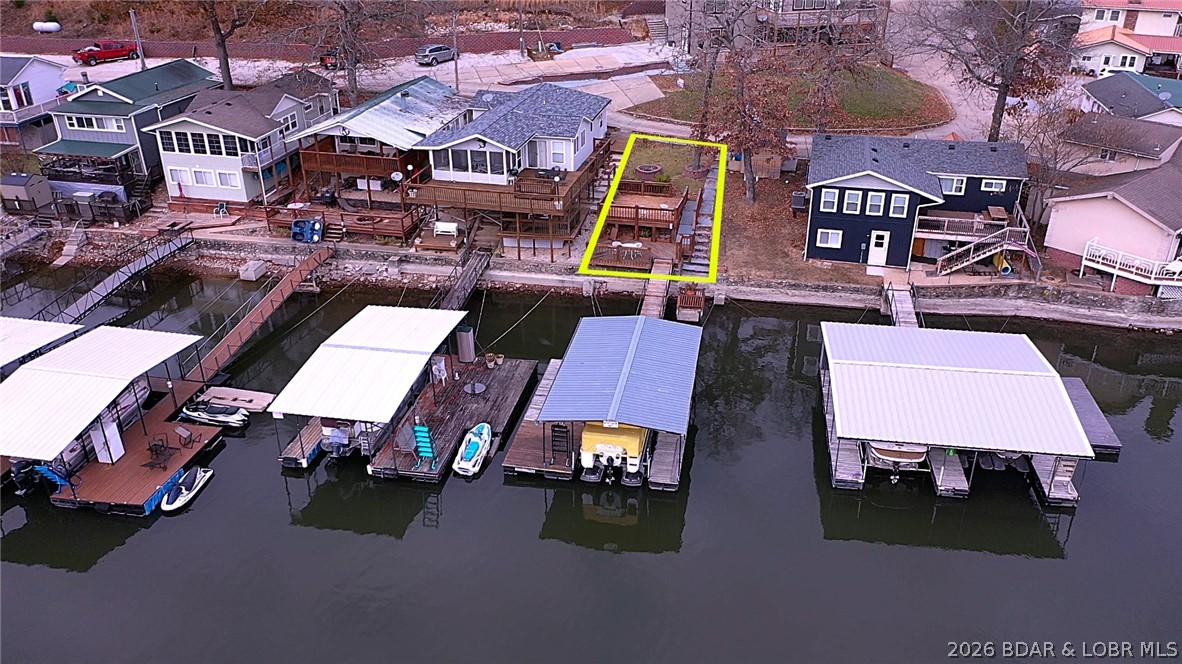 Aerial view of a yellow-outlined lakefront lot with a deck and covered boat docks.