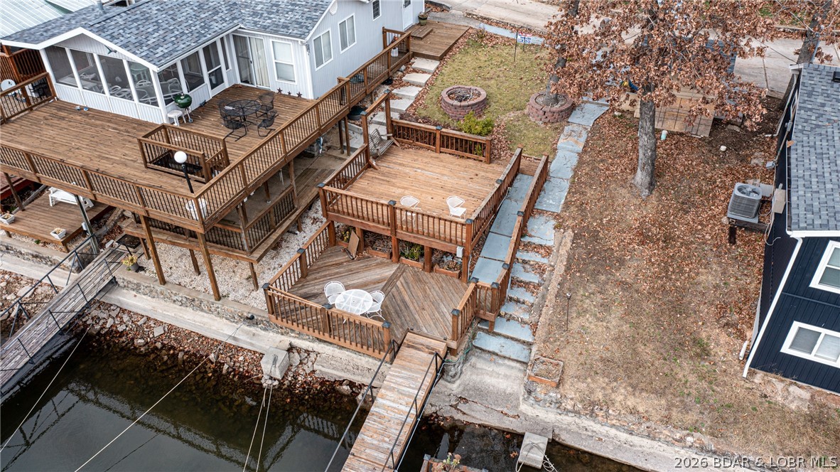 Aerial view of a lakeside home with tiered wooden decks and a dock along the shore.