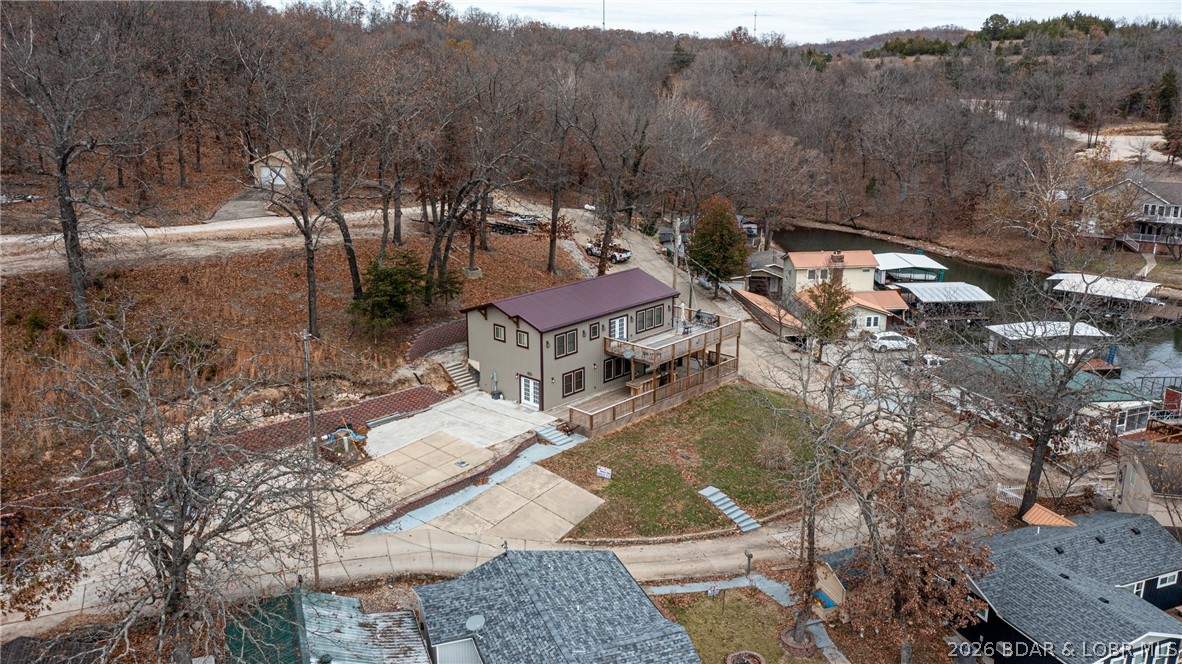 Aerial view of a two-story home with broad wooden decks beside a wooded cove.