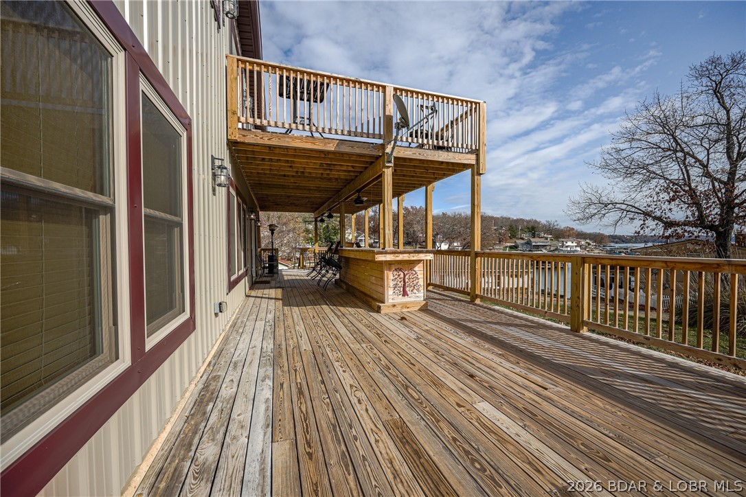 Spacious wooden deck with an upper balcony and a view of the lake.