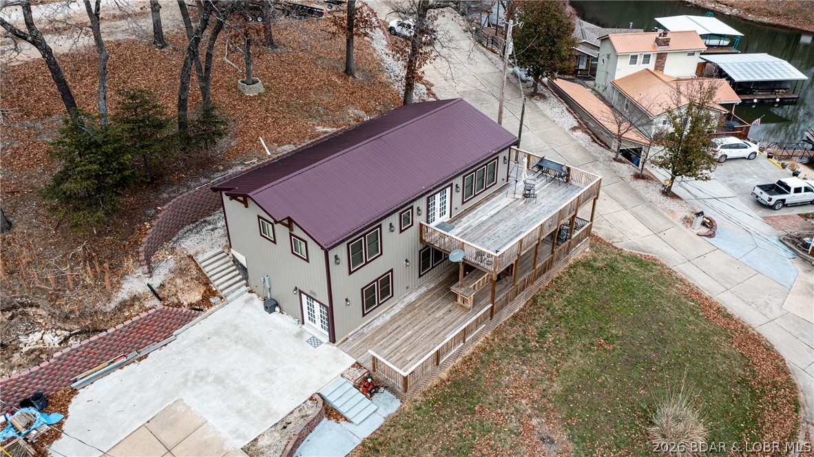 Aerial view of a two-story home with a burgundy roof and elevated wooden deck.