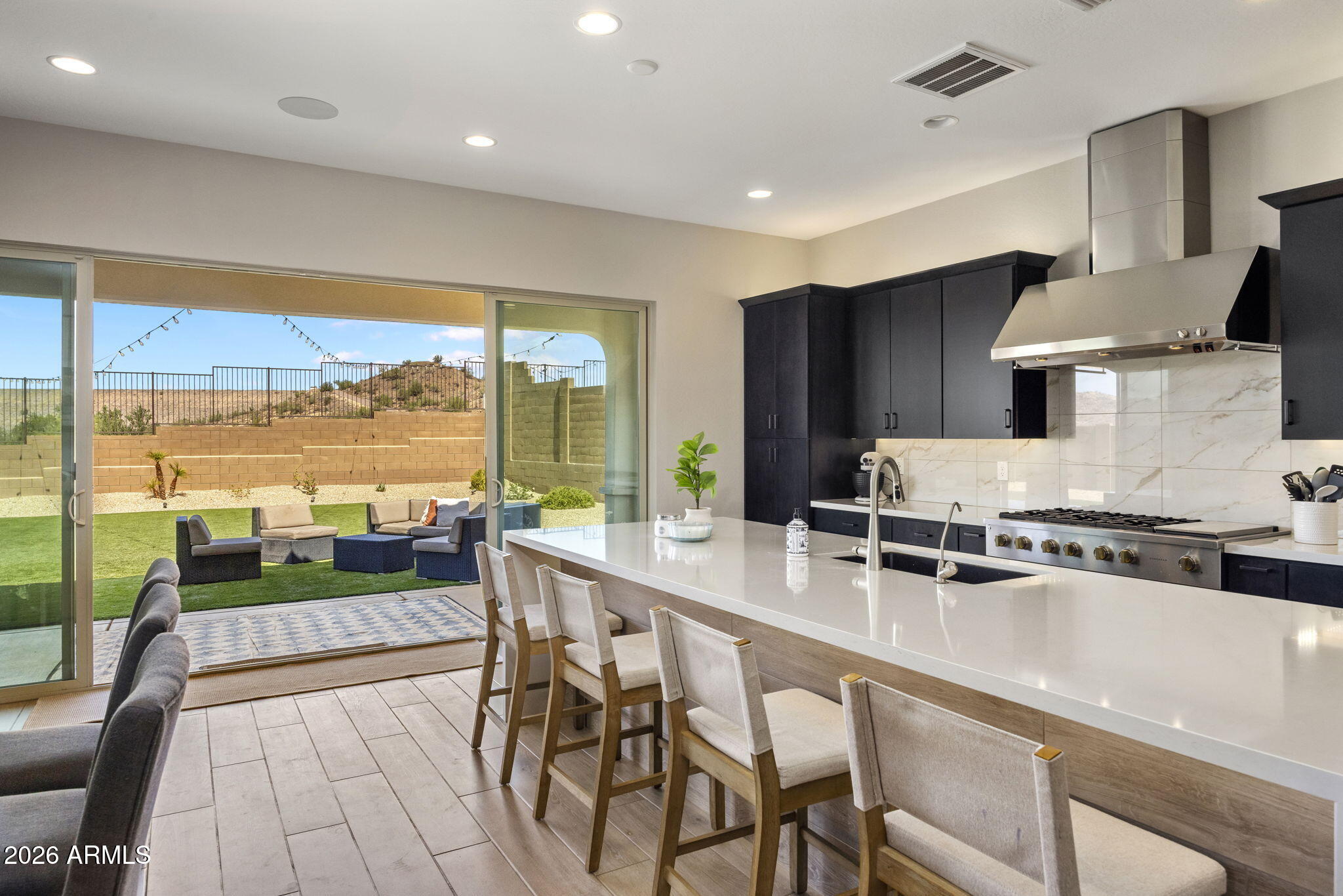 Modern kitchen with a large white island and sliding doors opening to a landscaped backyard.