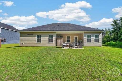Rear of a single-story tan house with a furnished patio and broad green lawn.