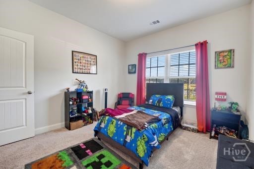 Bedroom with a colorful bedspread, pink curtains, and a multicolored rug.