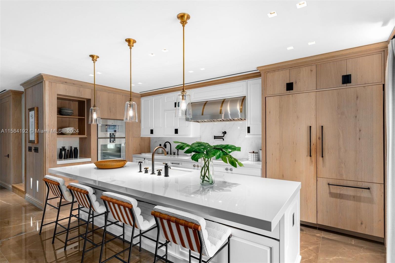 Modern kitchen with a white waterfall island, light wood cabinetry, and brass pendant lights.