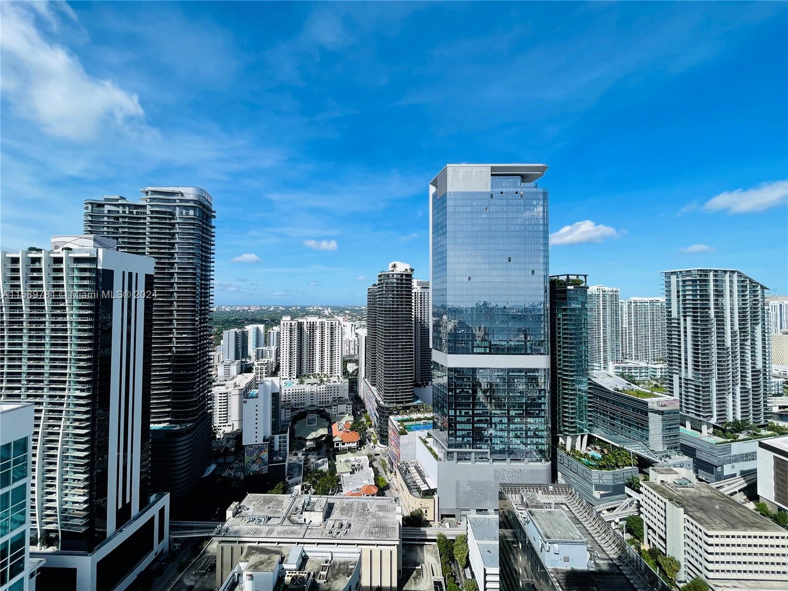 Miami skyline with a prominent glass tower surrounded by high-rise buildings.