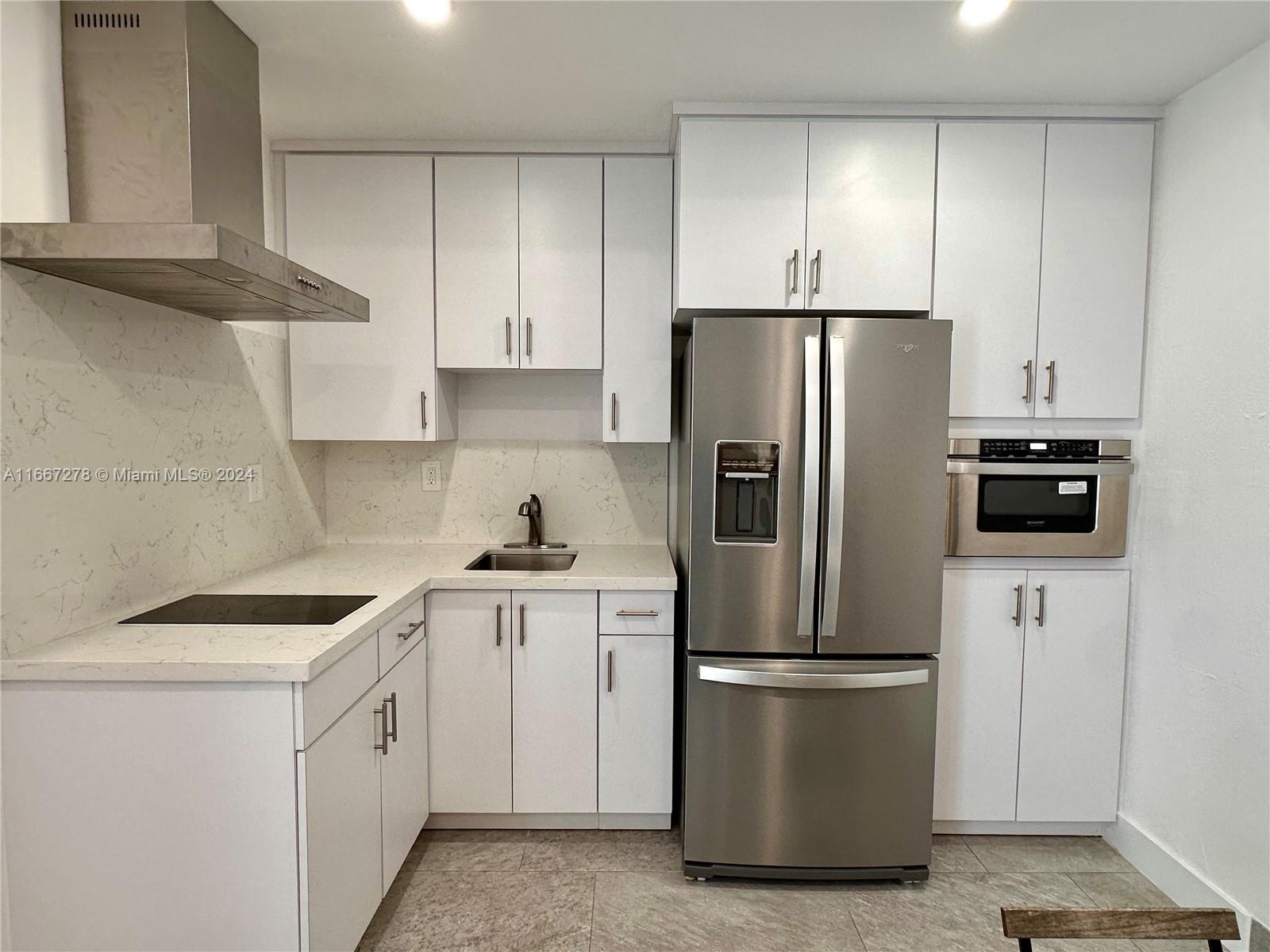Kitchen with white cabinetry, veined stone counters, and stainless steel appliances.