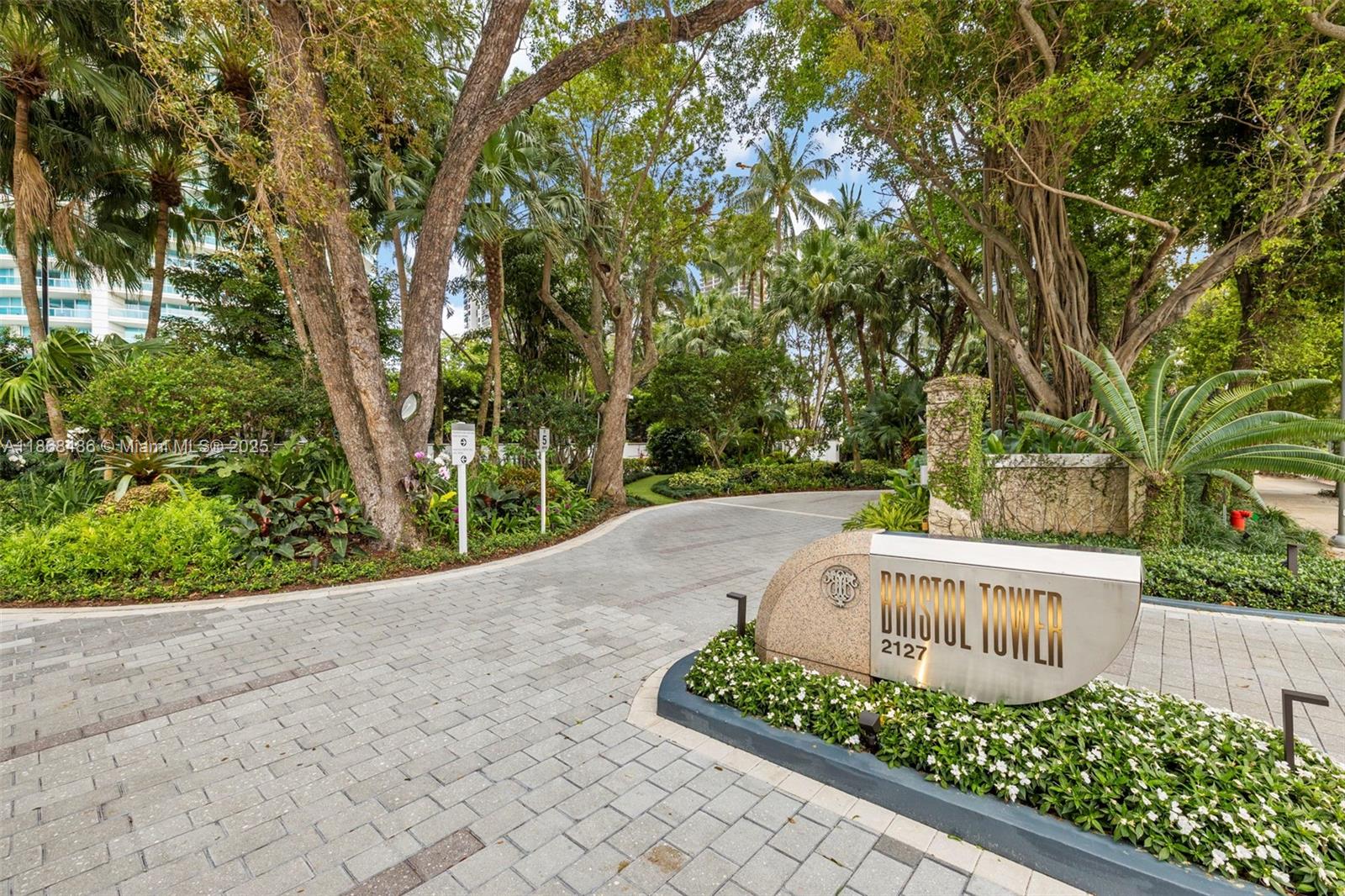Bristol Tower entrance at 2127, framed by tropical trees and landscaped grounds.