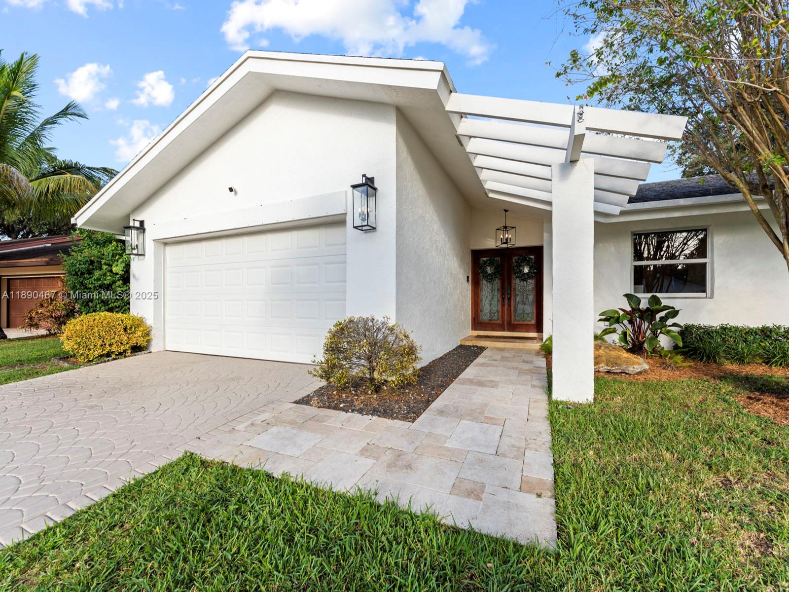 White single-story home with a sloped roof, double wooden entry doors, and a covered front walkway.
