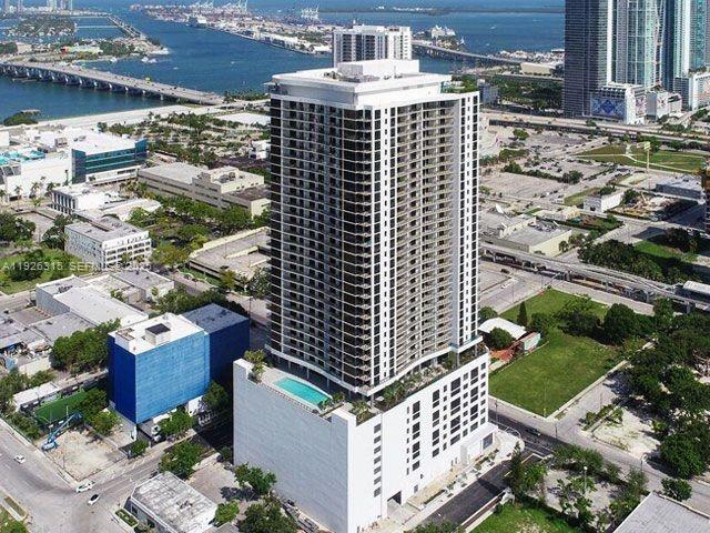 Aerial view of a white residential tower amid a waterfront cityscape.