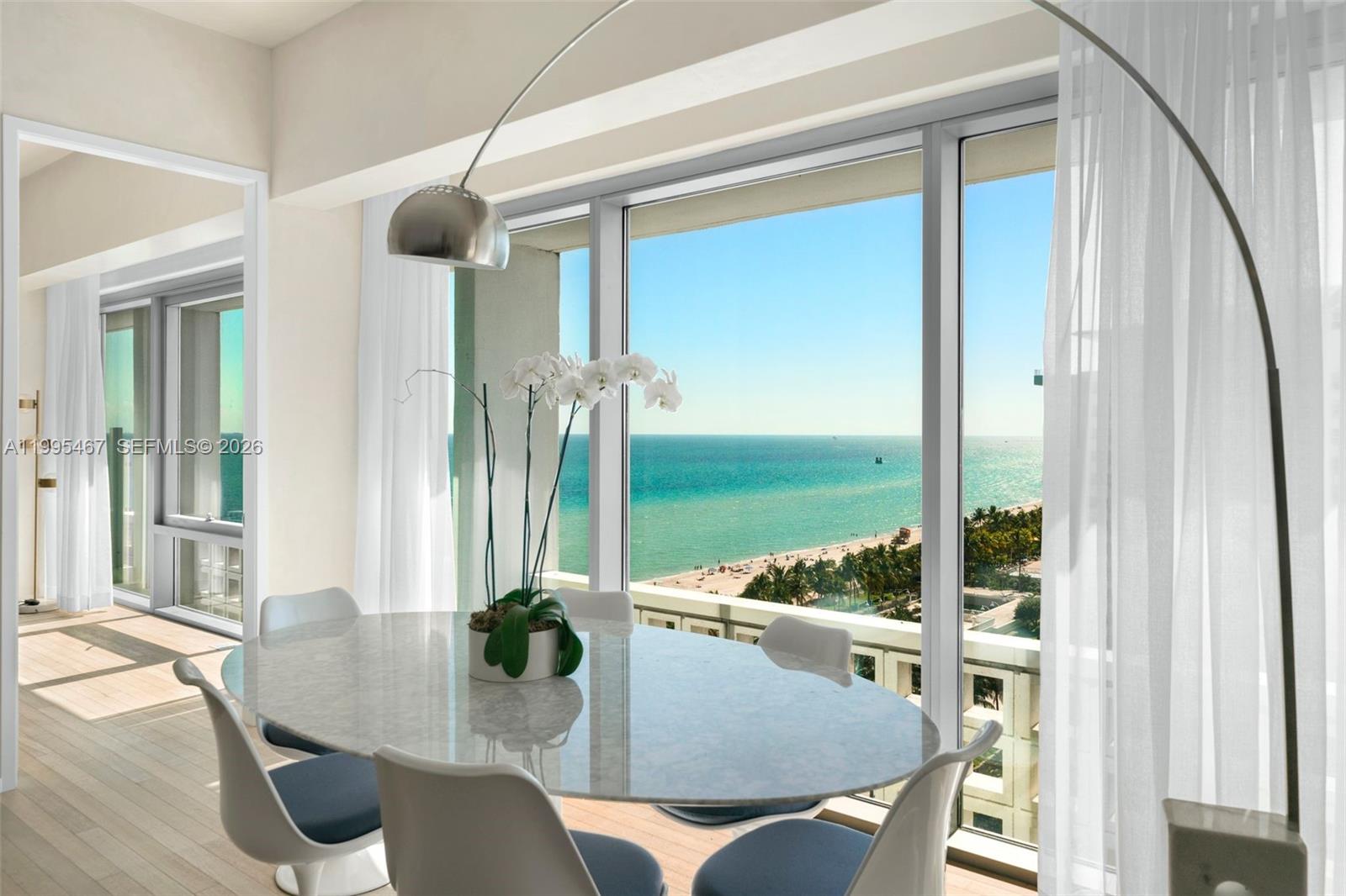 Dining area with floor-to-ceiling windows overlooking the ocean and beach.