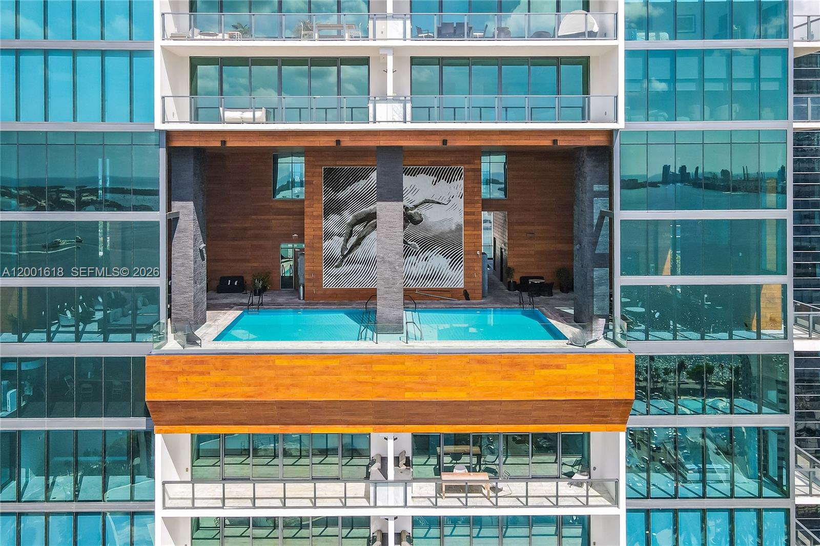 Modern glass condominium facade with a projecting pool and wood-clad central section.