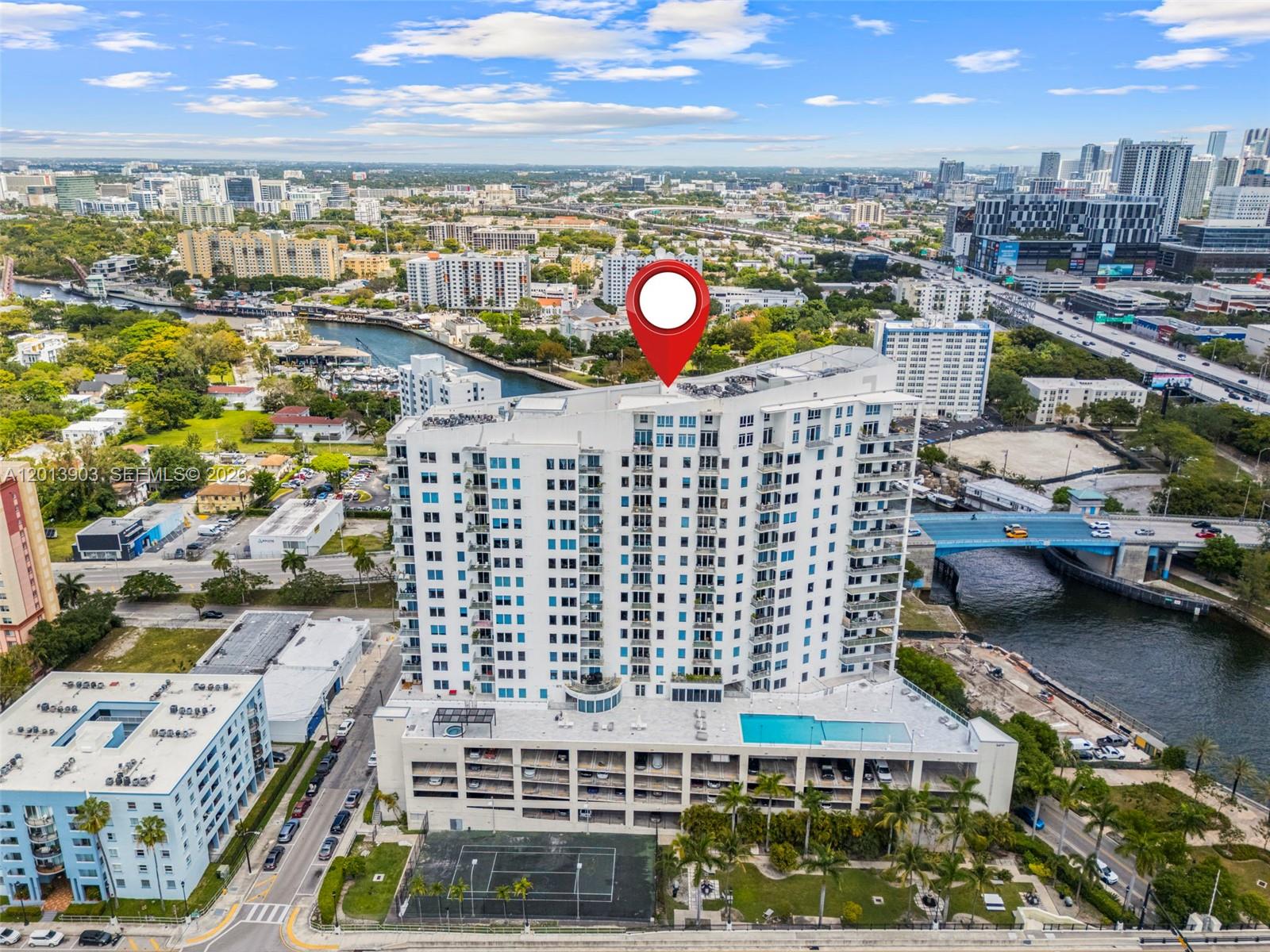Aerial view of a white condominium beside a canal, marked with a red location pin.