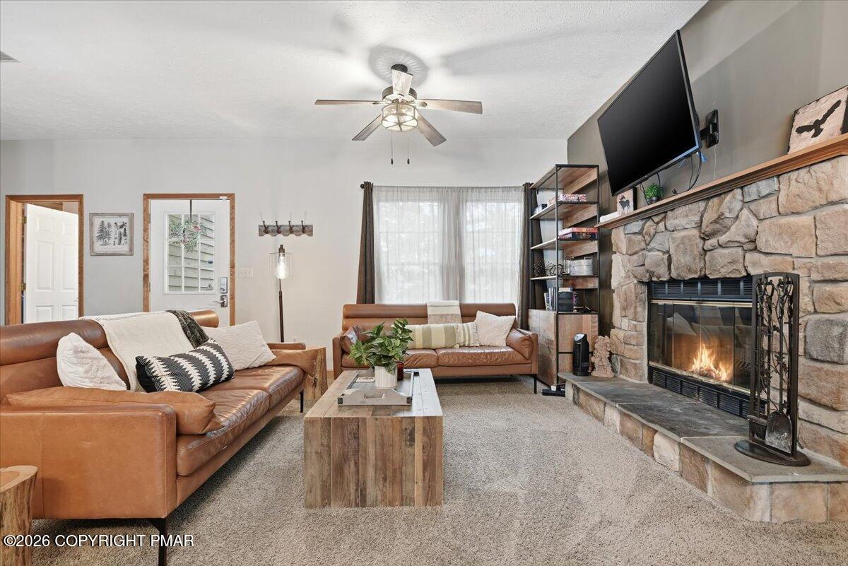 Living room with a stone fireplace, leather seating, and a wood coffee table.