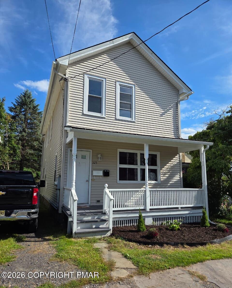 Two-story beige house with a white covered porch and front steps.