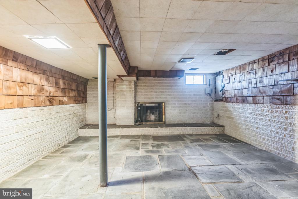 Unfurnished basement with stone-tile flooring and a fireplace at the far end.
