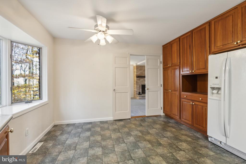 Kitchen with dark wood cabinets, gray tile flooring, and double doors opening toward a brick fireplace.