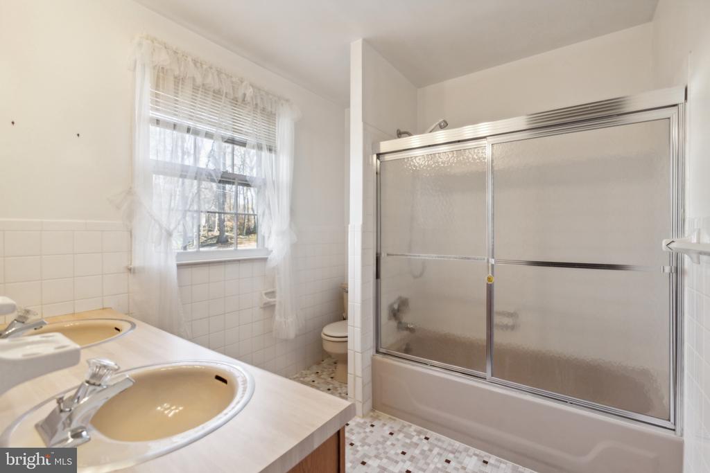 Bathroom with a double-sink vanity and a bathtub behind sliding frosted-glass doors.
