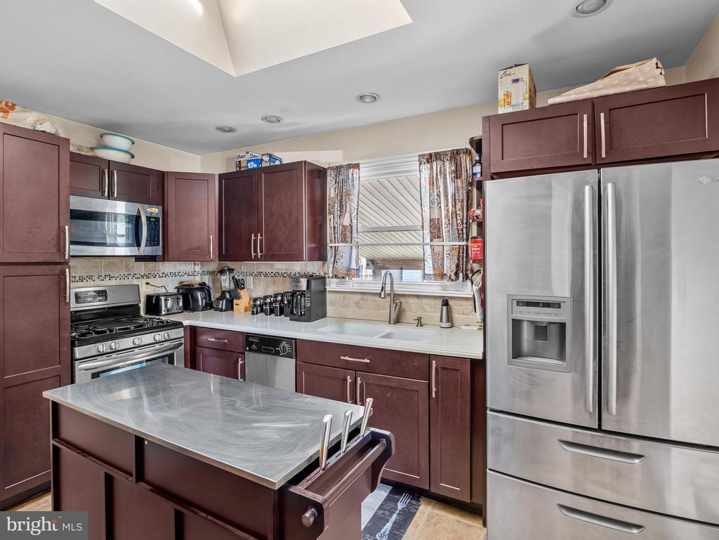 Kitchen with dark cabinets, stainless steel appliances, and a large island.