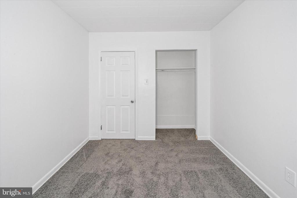 Empty bedroom with gray carpet, white walls, and an open closet.