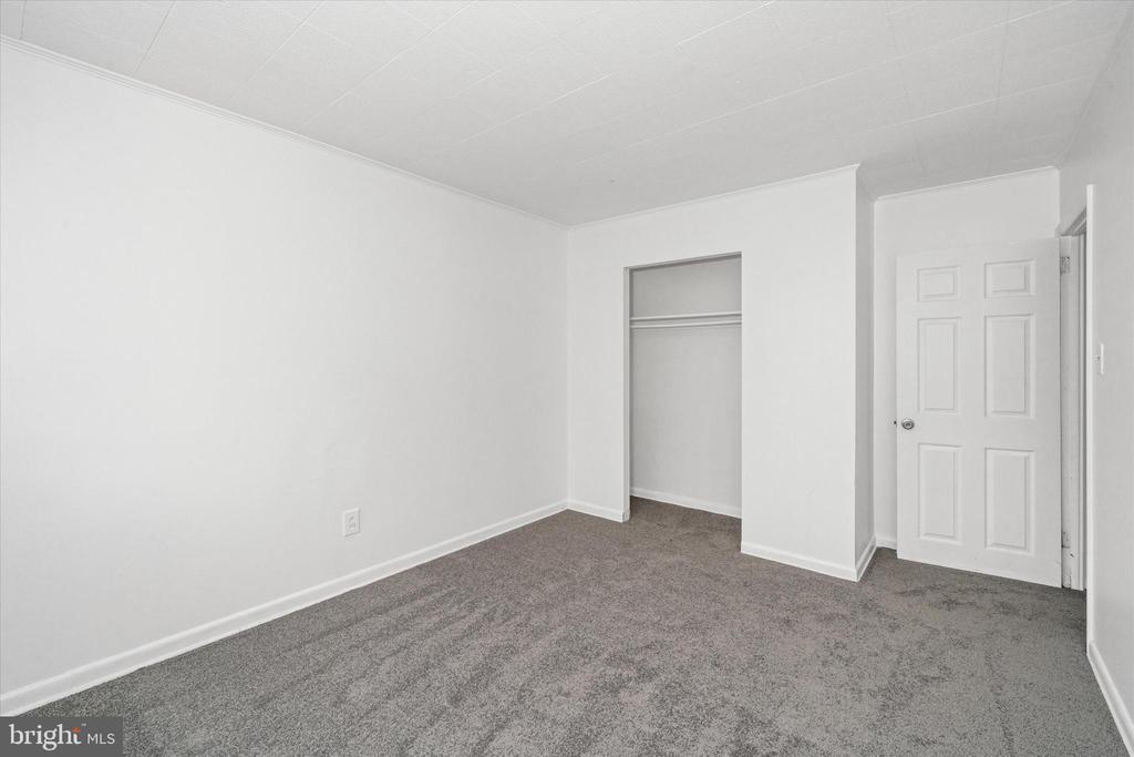 Empty bedroom with gray carpet, a built-in closet, and a white paneled door.