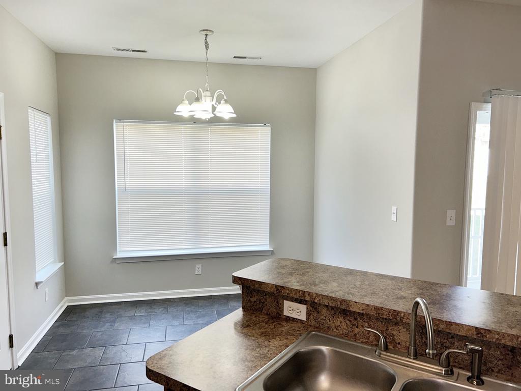 Kitchen with a granite-patterned peninsula, double-basin sink, and chandelier over a tiled dining nook.