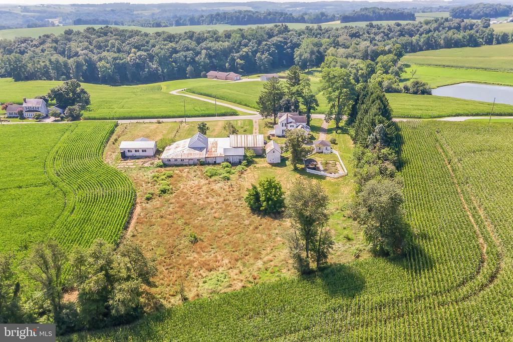 Rural farm property with a farmhouse and agricultural buildings amid cultivated fields.