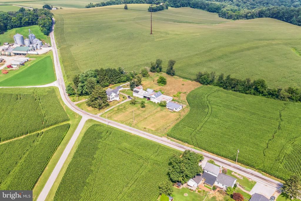 Aerial view of a rural farmstead surrounded by crop fields and intersecting country roads.