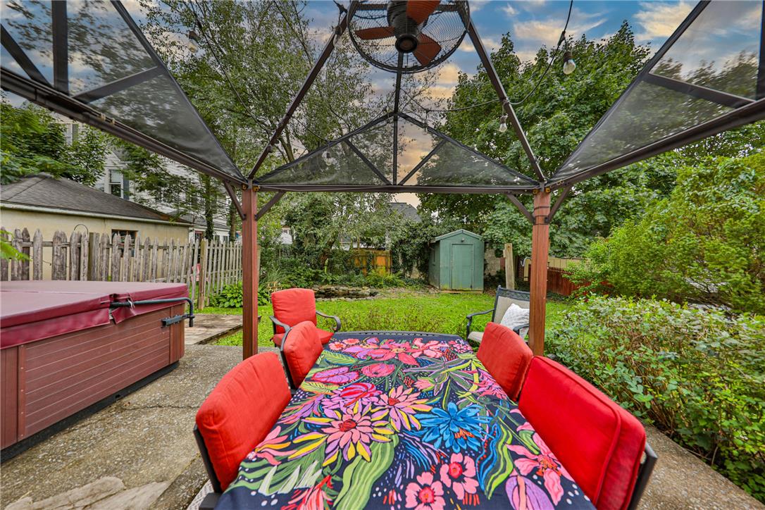 Backyard patio with a hot tub and colorful dining set beneath a gazebo.