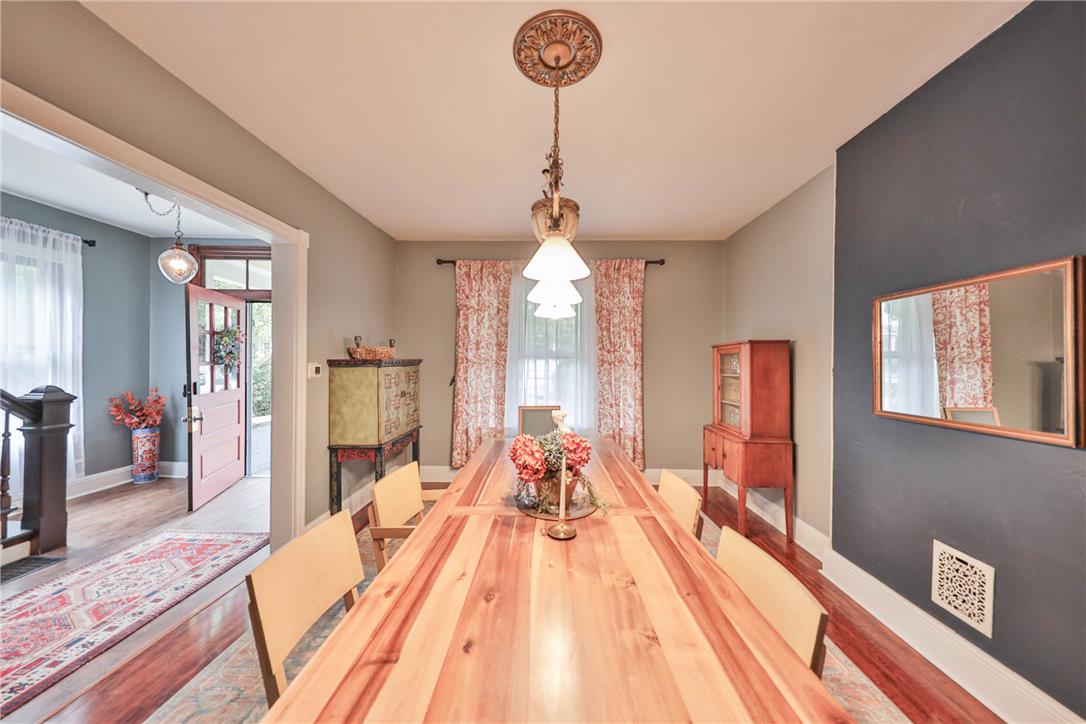 Dining room with a long natural-wood table, pendant chandelier, and patterned curtains.