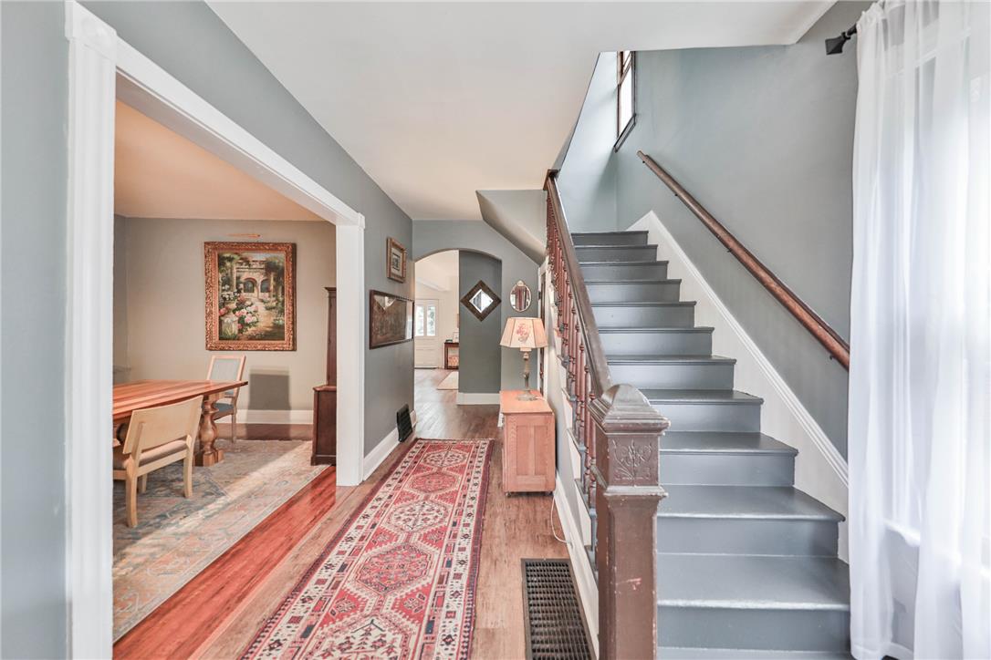 Foyer with a gray staircase, patterned runner, and view into the adjoining dining room.