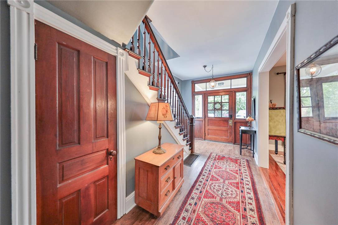 Foyer with a wood staircase, matching front door, hardwood floors, and a patterned runner.