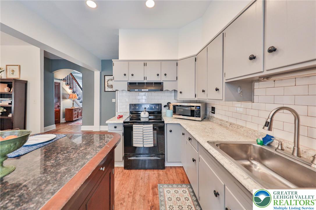 Kitchen with white cabinetry, granite counters, stainless appliances, and a double-basin sink.