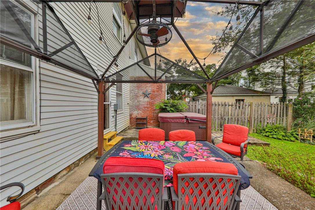 Backyard patio with a canopy-covered dining set and hot tub beside the house.