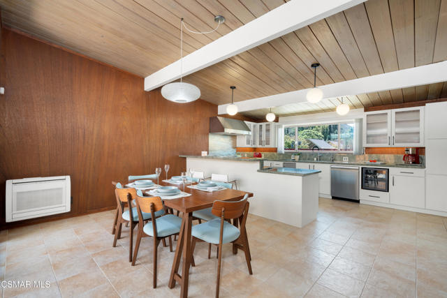 Open kitchen and dining area with wood-paneled ceiling, island, and set table.