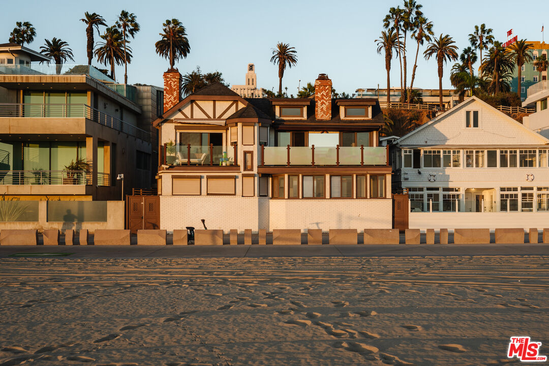 Beachfront homes with glass balconies and brick chimneys in warm evening light.