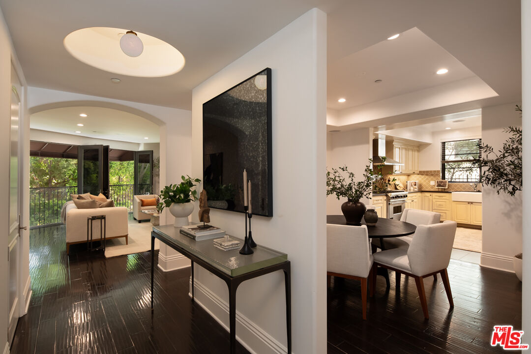 Open-plan living room, dining area, and kitchen with dark wood floors and balcony doors.