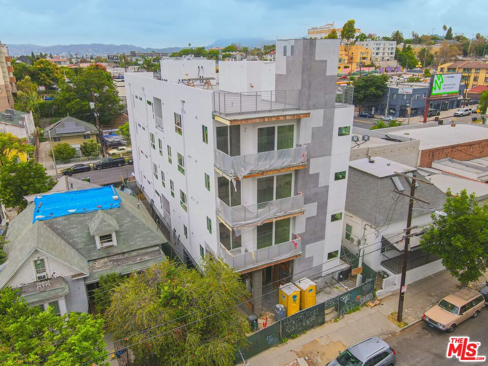 Aerial view of a white-and-gray apartment building under construction, with balconies and temporary fencing.