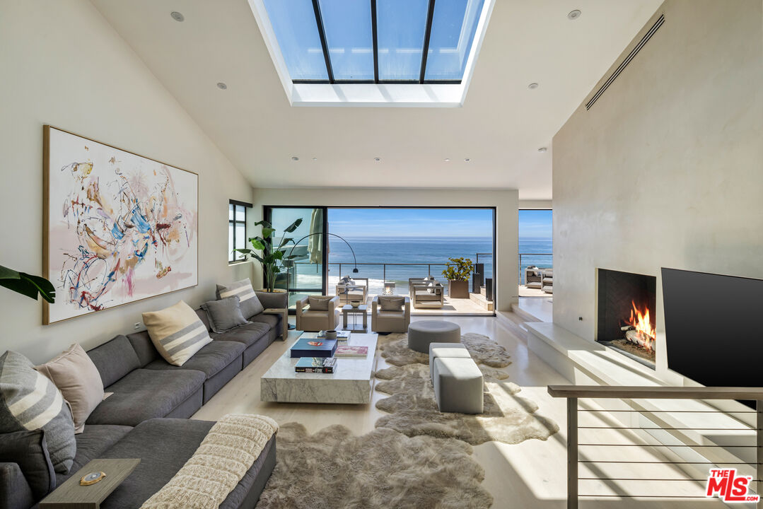 Modern living room with a skylight, fireplace, and panoramic ocean views.