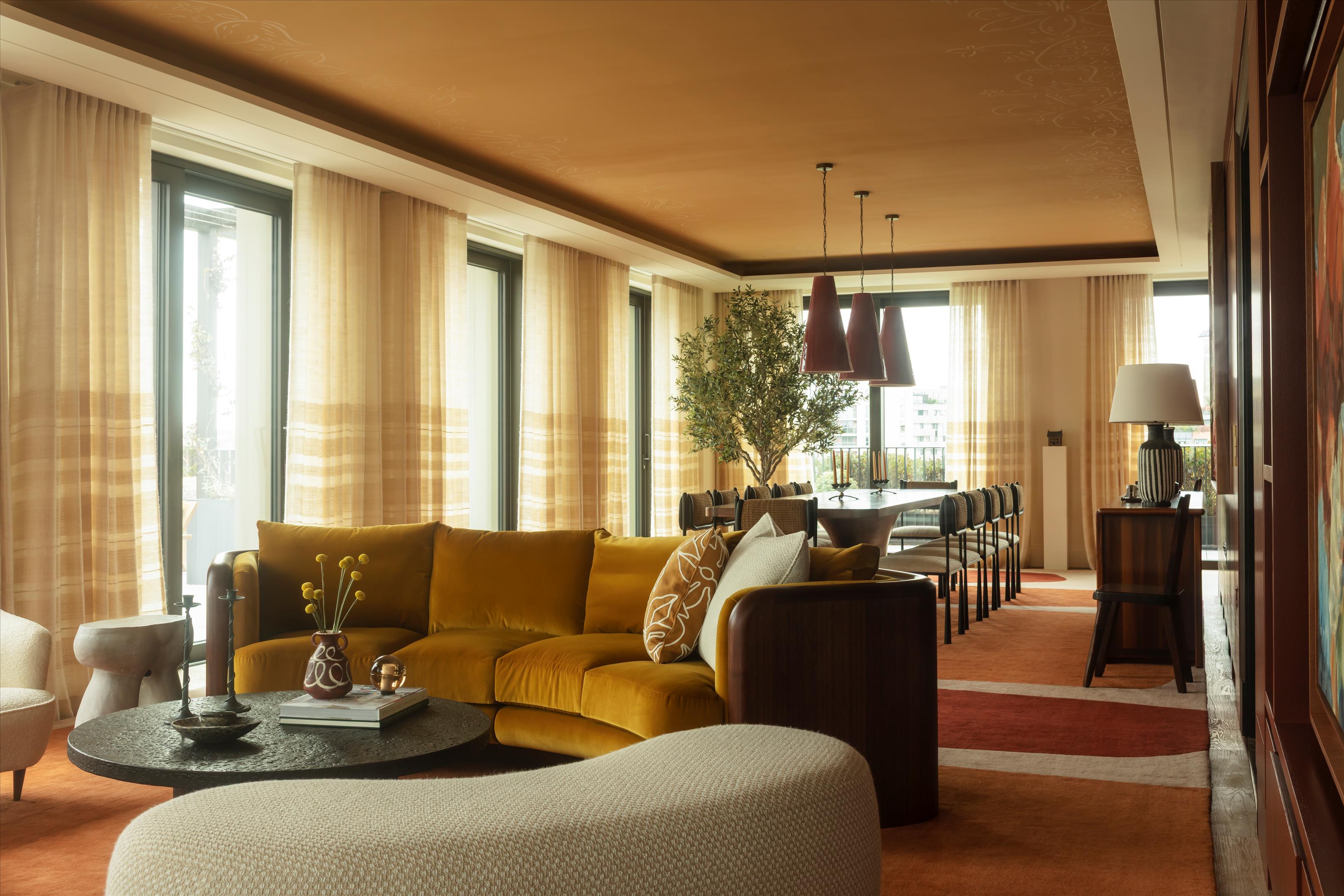 Living and dining room with a mustard-yellow sectional and three pendant lights over the dining table.
